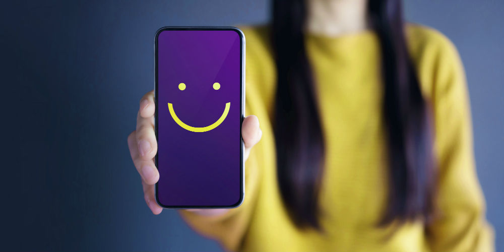Person holding up a phone with smiley face